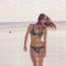 Playful woman in bikini dancing in sea water on summer beach. Happy woman in swimsuit dancing on sea